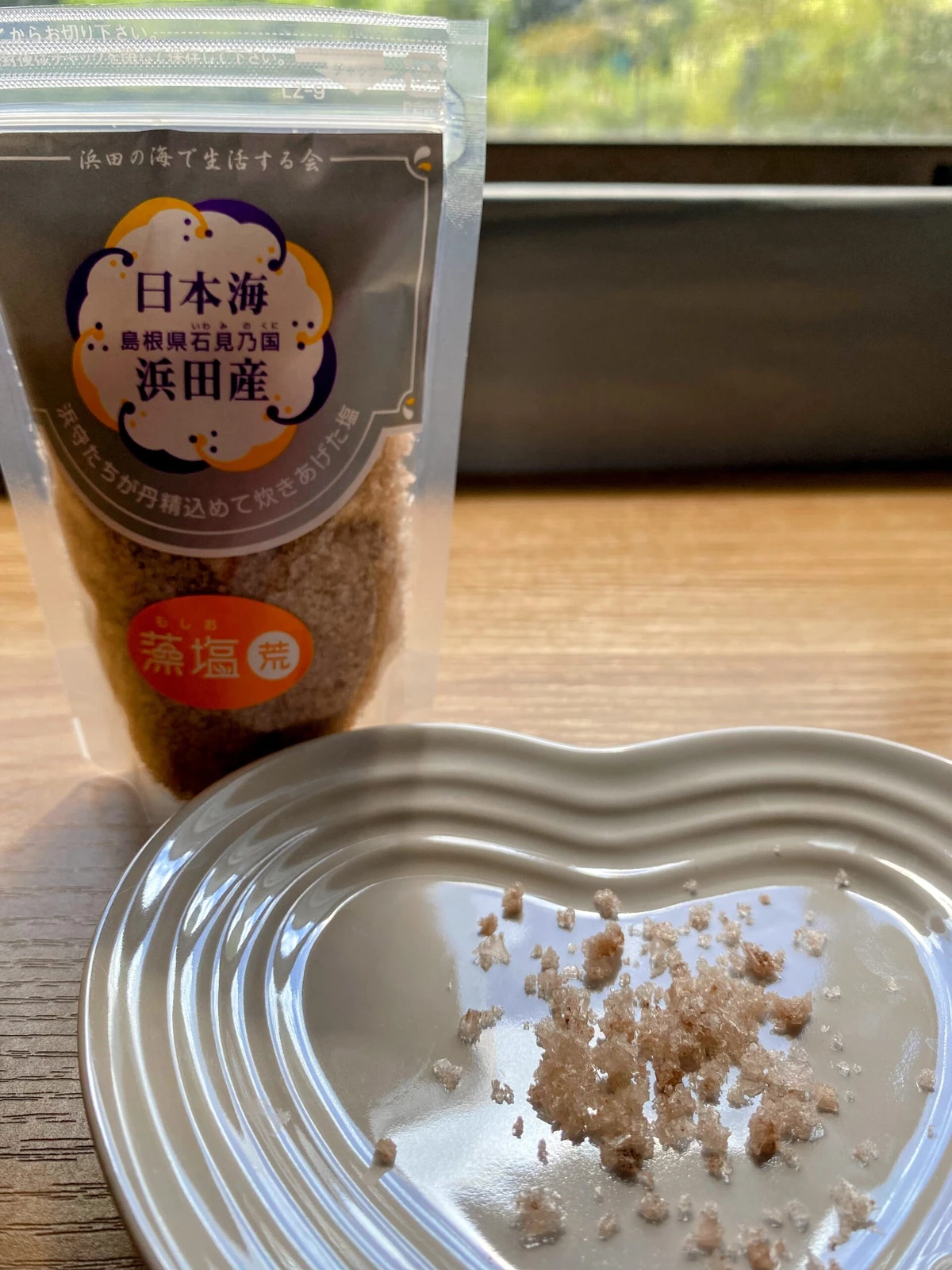 Coarse Japanese moshio seaweed salt grains beside the package