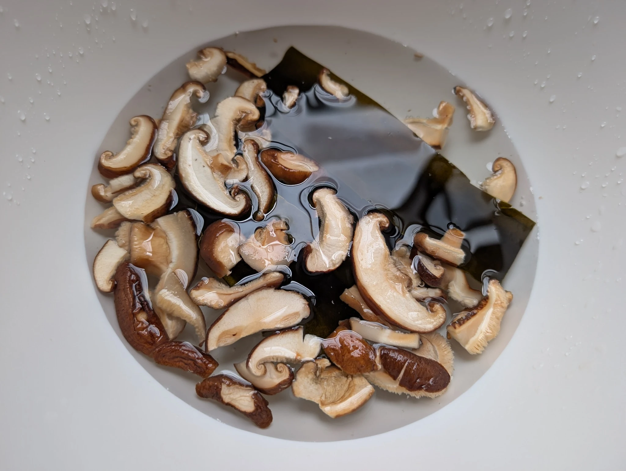 Kombu and sliced dried shiitake mushrooms soaking in water for vegan dashi