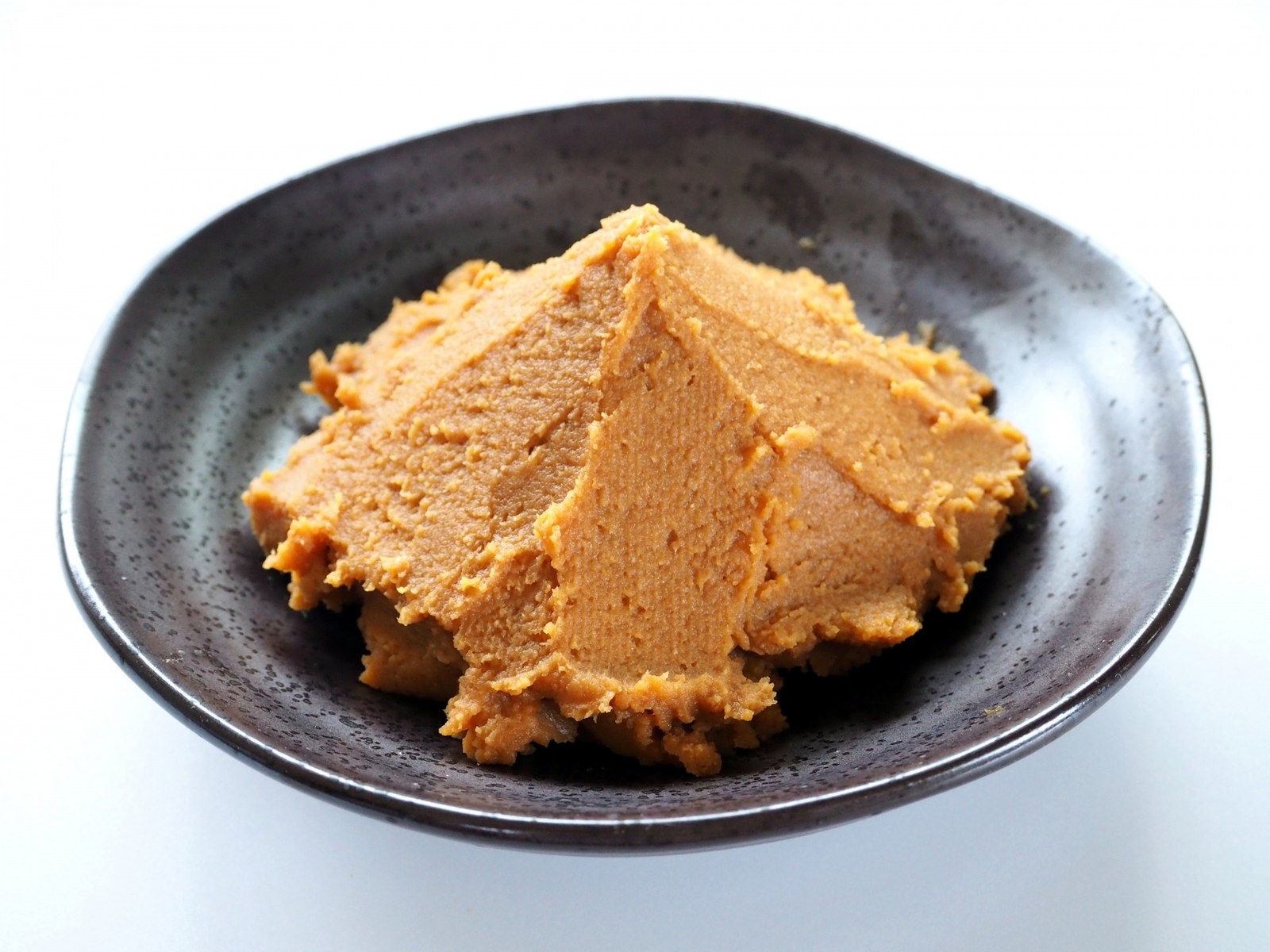Light brown Japanese miso paste on a dark ceramic plate