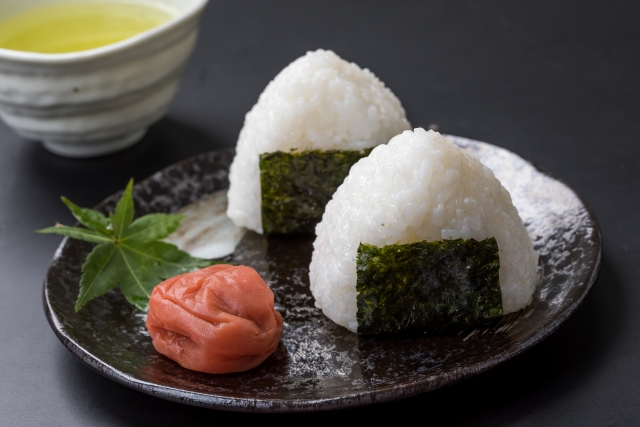 Two Japanese vegan onigiri rice balls served with umeboshi on a plate